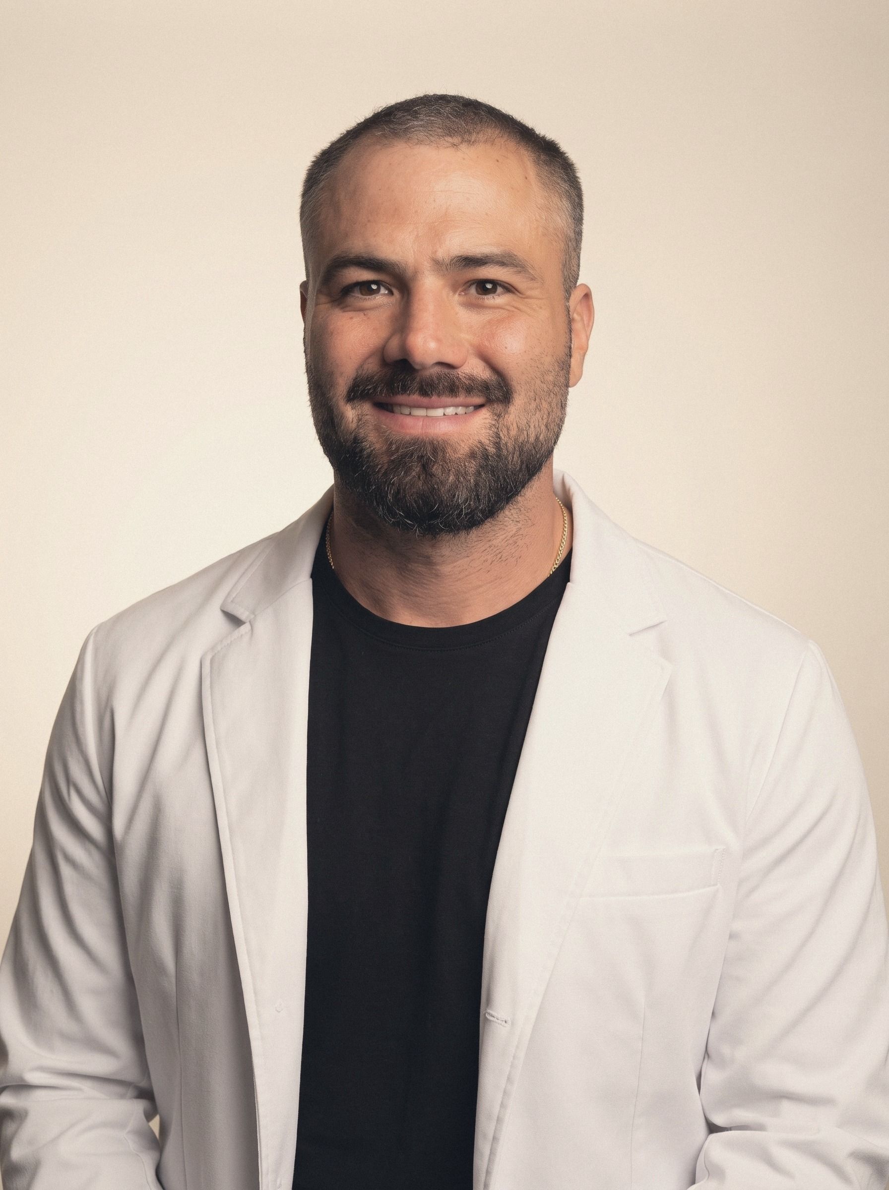 Dr. Ricardo Campos con bata blanca abierta sobre playera negra, sonriendo